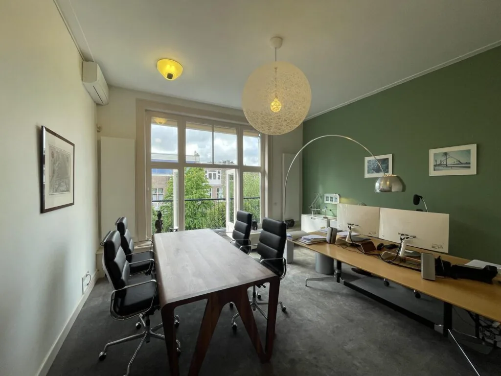 Modern kantoor met vergadertafel, bureaus en uitzicht op de Oranje Nassaulaan door grote ramen.